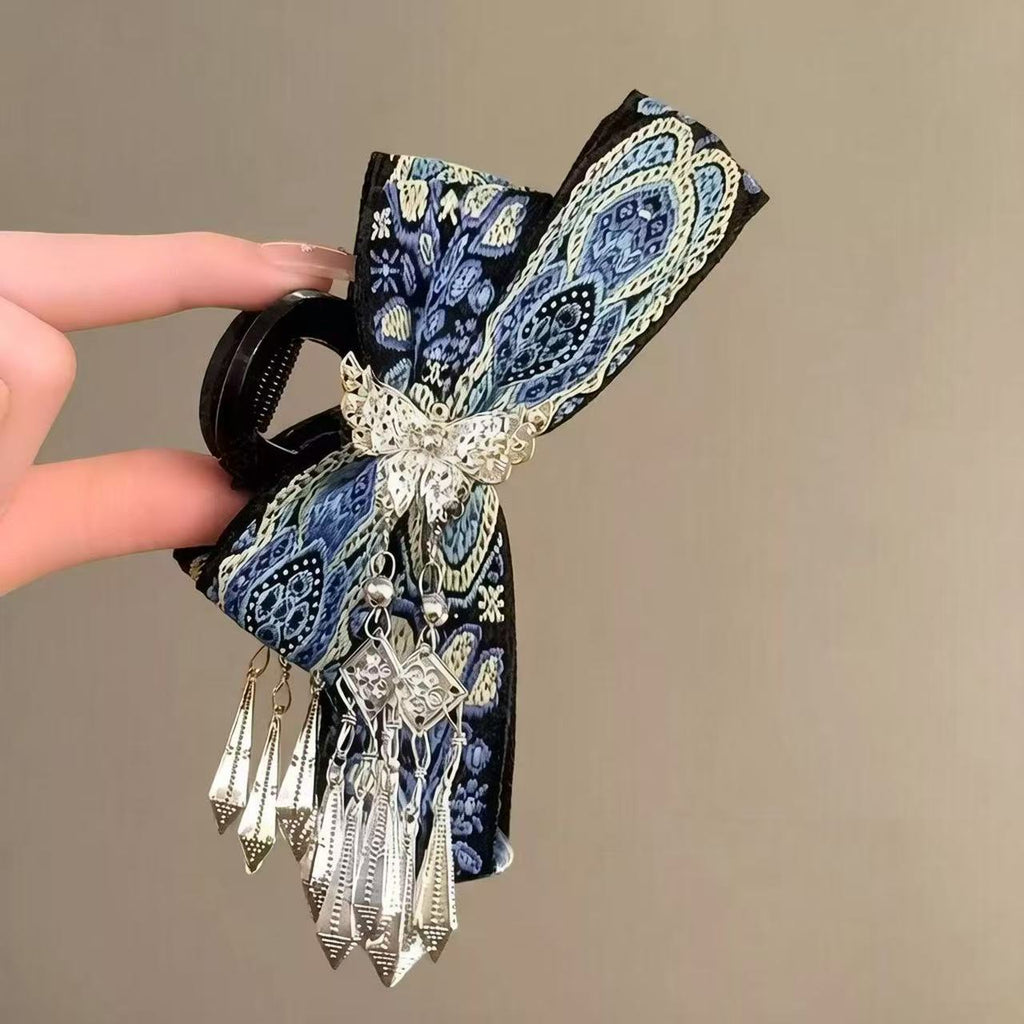 Close-up of blue paisley embroidered bow hair claw clip with silver tassels