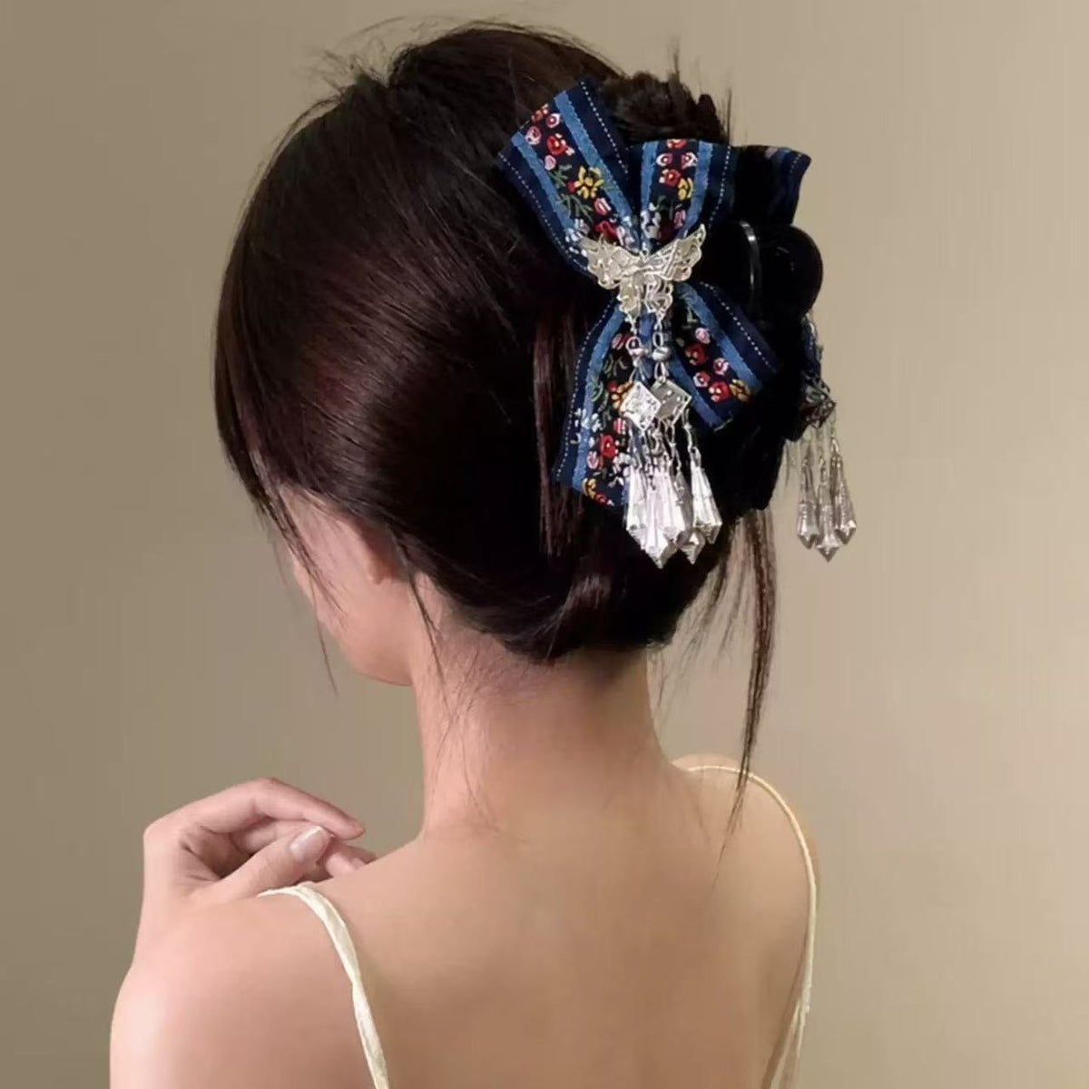 Embroidered bow hair claw clip with butterfly and crystal tassels worn in updo