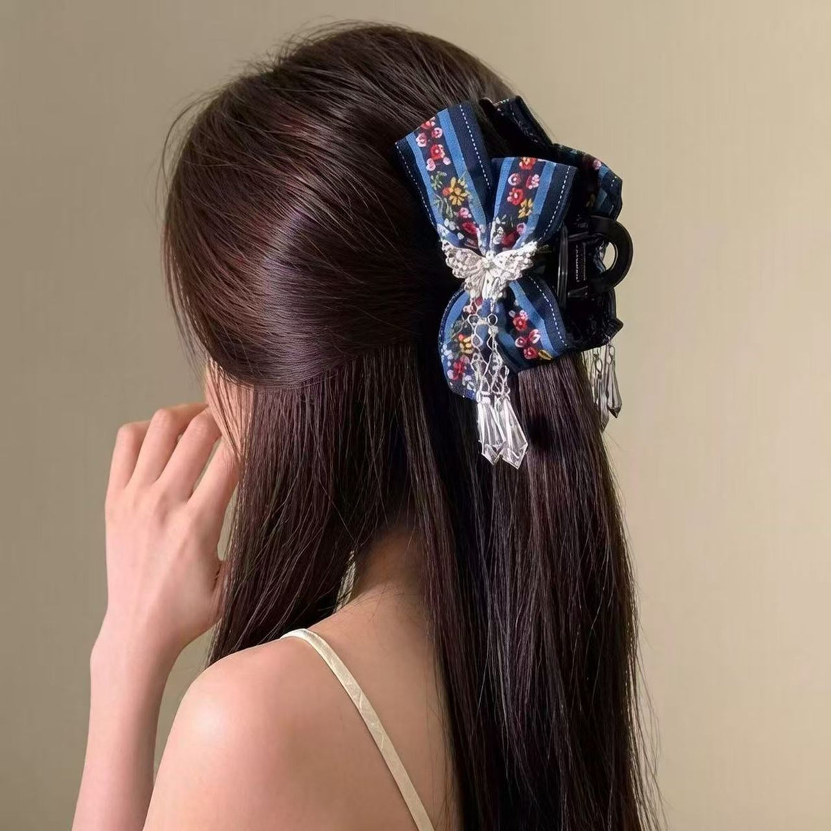 Embroidered bow hair claw clip worn in half-up hairstyle with crystal tassels