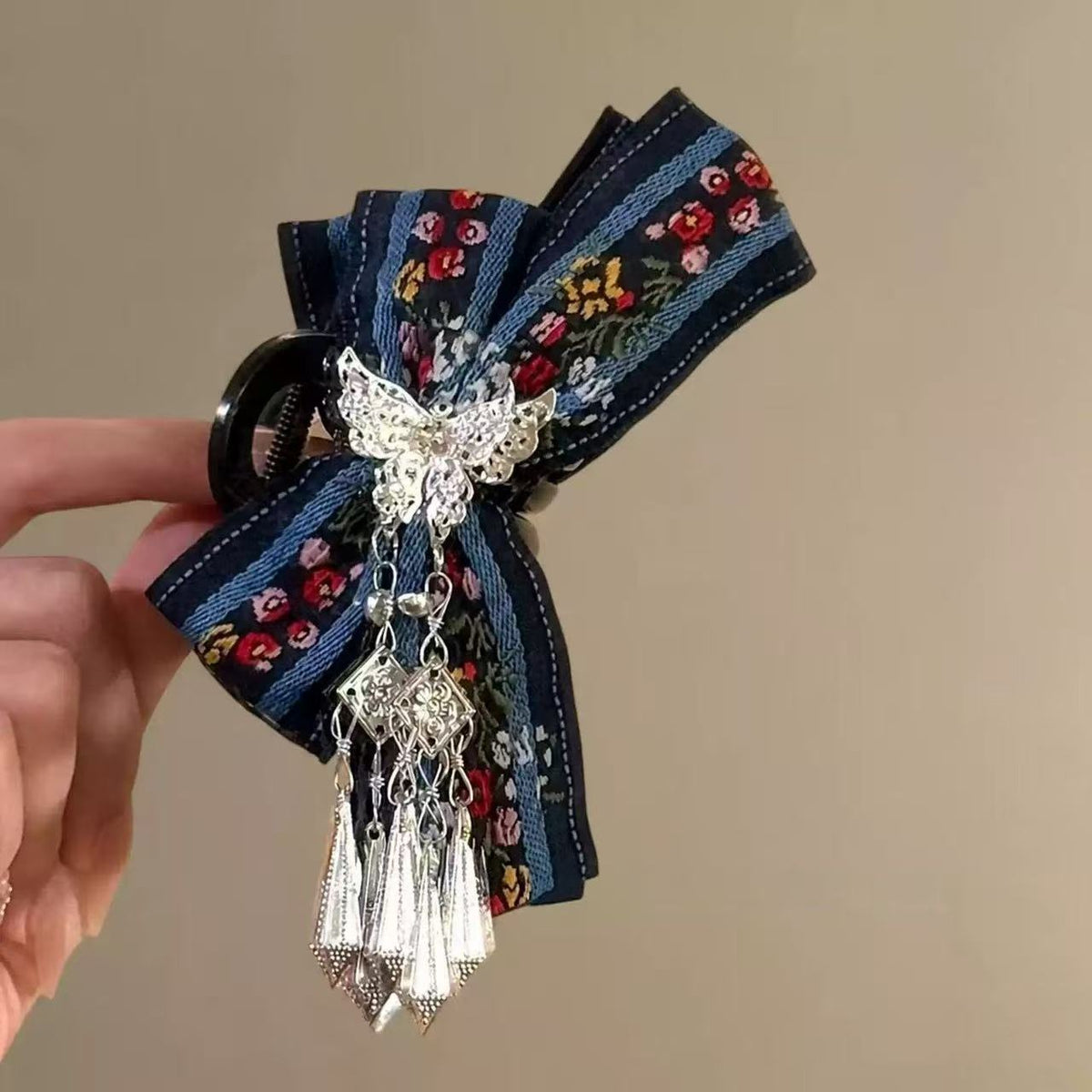 Close-up of navy floral embroidered bow hair claw clip with butterfly centerpiece